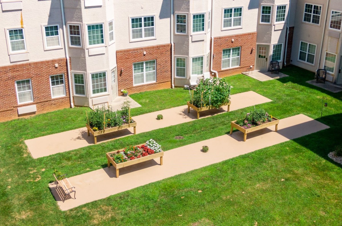 A garden with raised beds filled with vegetables and plants in front of a building.