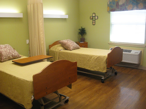 A well-lit hospital room featuring two adjustable patient beds with yellow bedding.