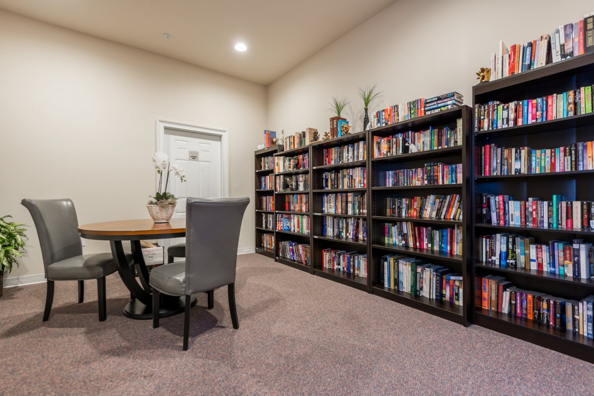 A cozy reading room with a large bookshelf filled with books and a small table and chair set.