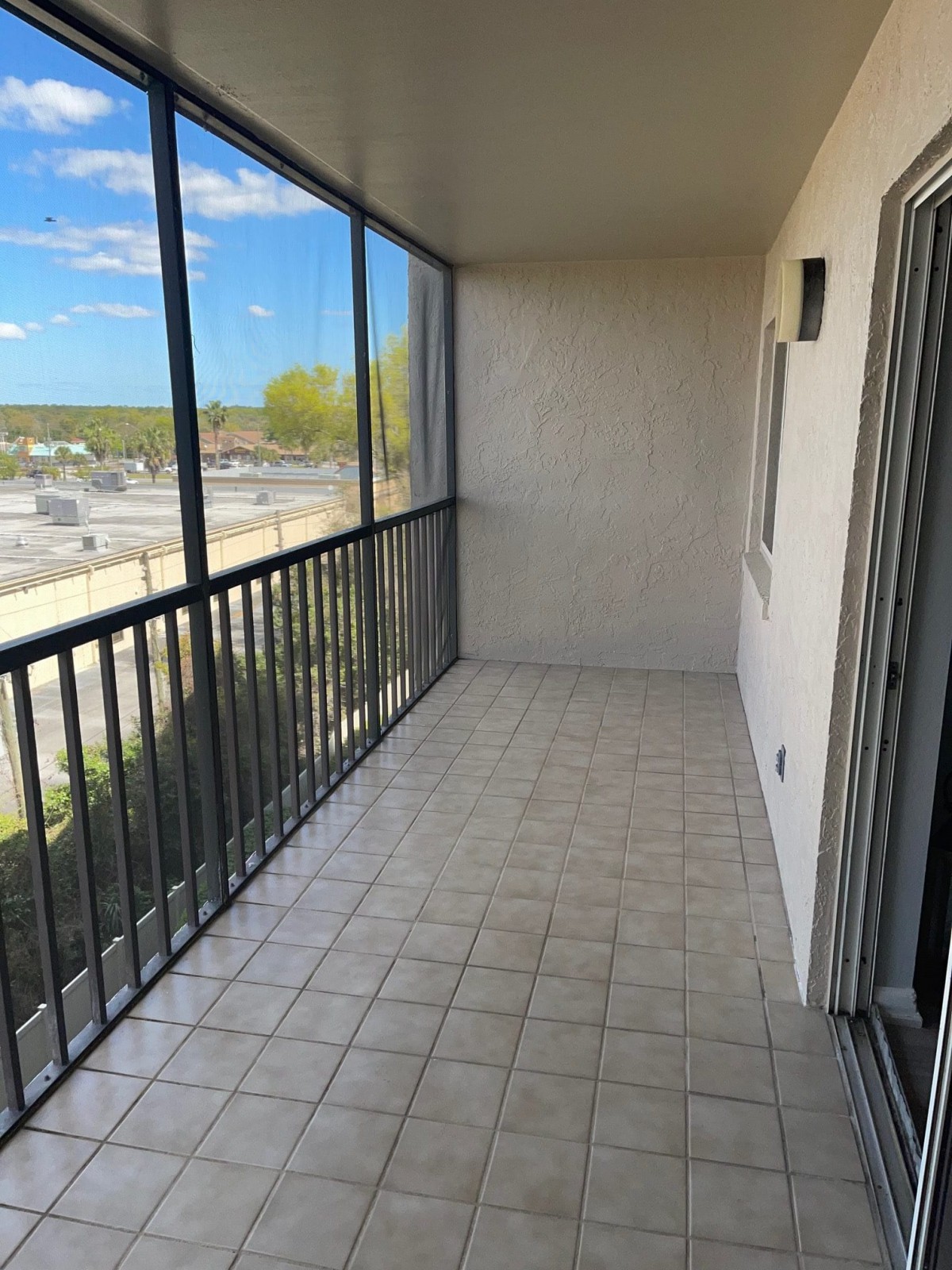 A spacious screened-in balcony with tiled flooring and a scenic view.
