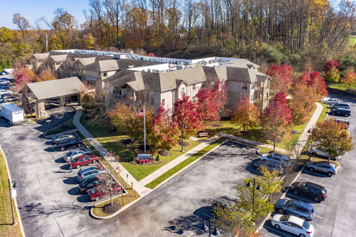 Aerial view of a residential complex surrounded by autumn trees and a parking lot.