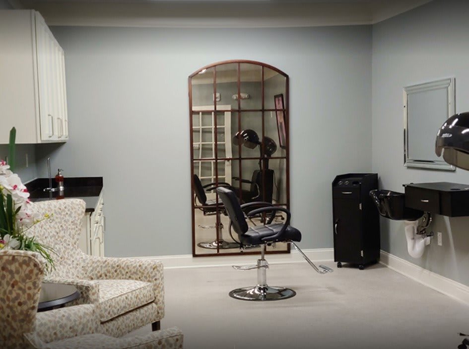 A modern salon interior with a styling chair, mirror, and sink.