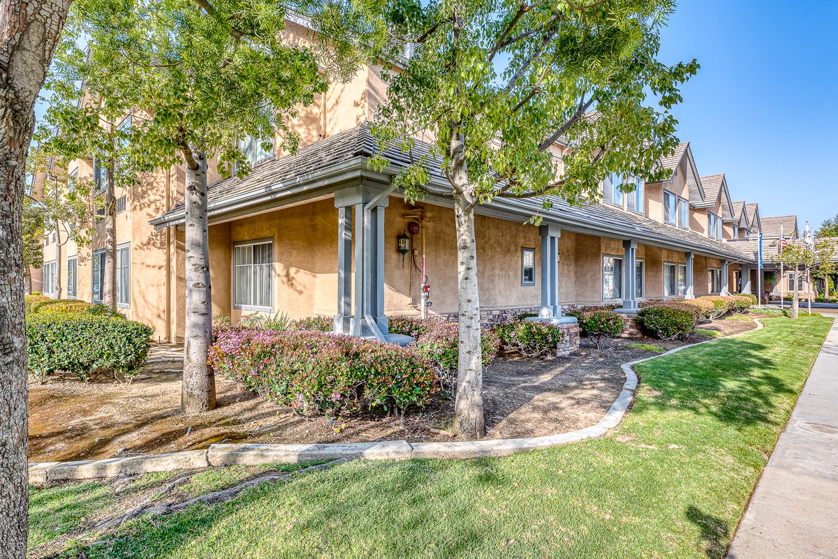A beautiful residential house with a landscaped front yard, featuring trees and green grass.