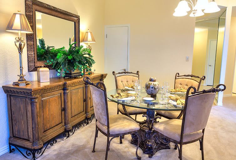 Elegant dining room with a glass table, upholstered chairs, and decorative elements.