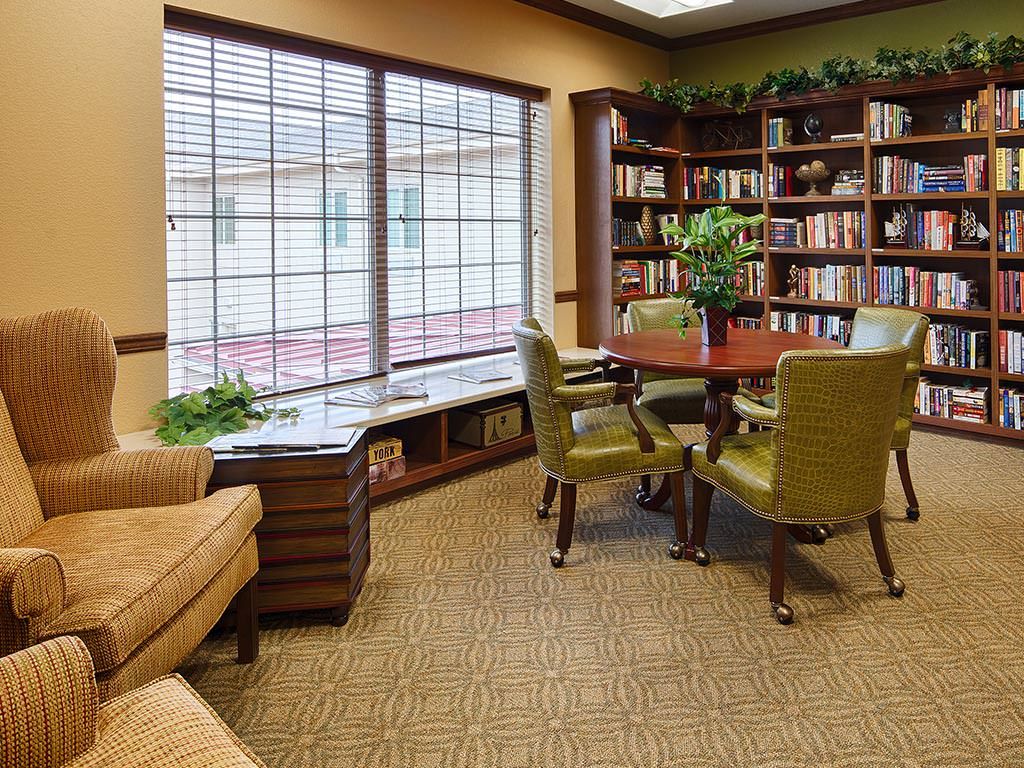 A cozy library reading room with bookshelves, a table, and comfortable seating.
