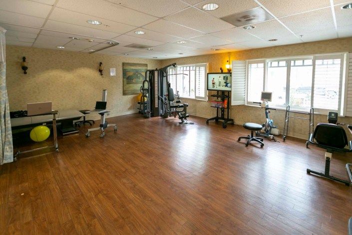 A spacious gym area with exercise equipment and wooden flooring.