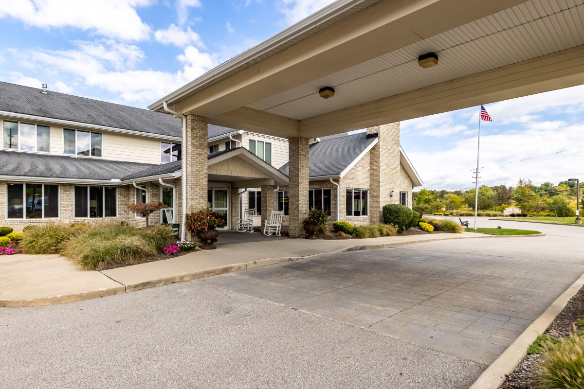 The exterior of a building with a covered driveway and surrounding greenery.