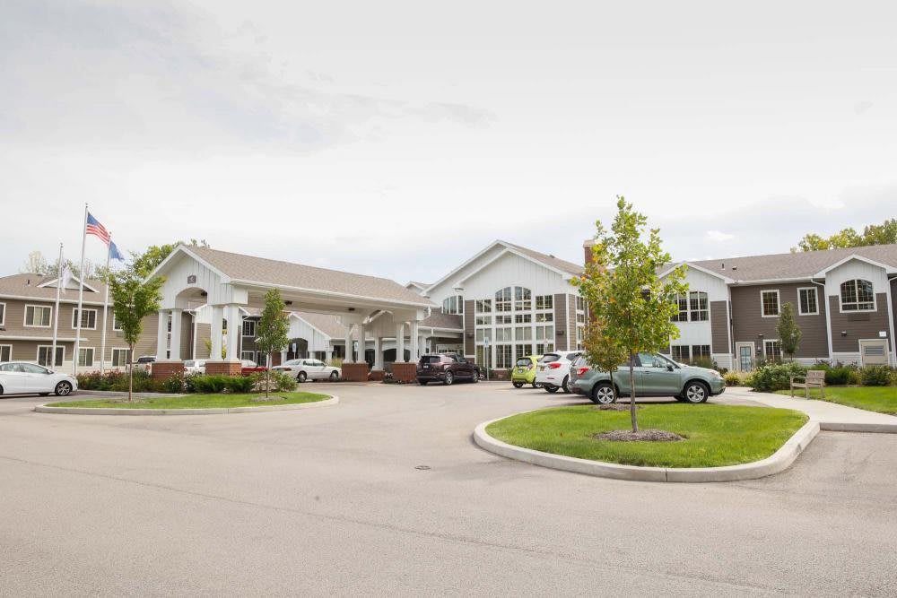A modern building with a landscaped parking area and several parked cars.