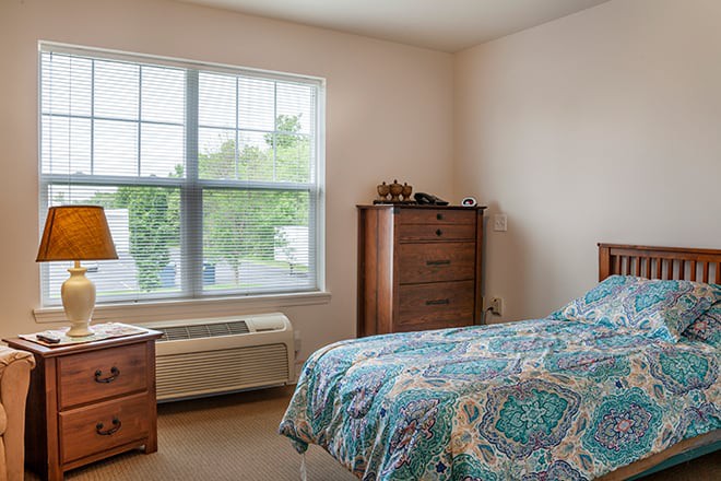 A cozy bedroom with a large window and patterned bedspread.