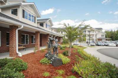 A suburban residential building with a landscaped garden and statue in the foreground.