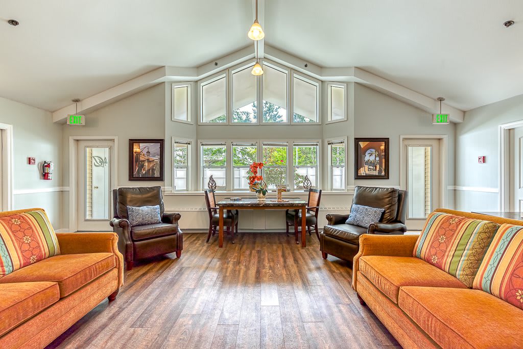 A spacious and well-lit living room featuring comfortable sofas, armchairs, and large windows allowing natural light to fill the space.