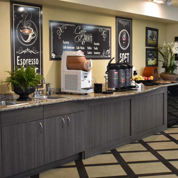 A self-service coffee station featuring an espresso machine and beverage dispensers on a modern countertop.
