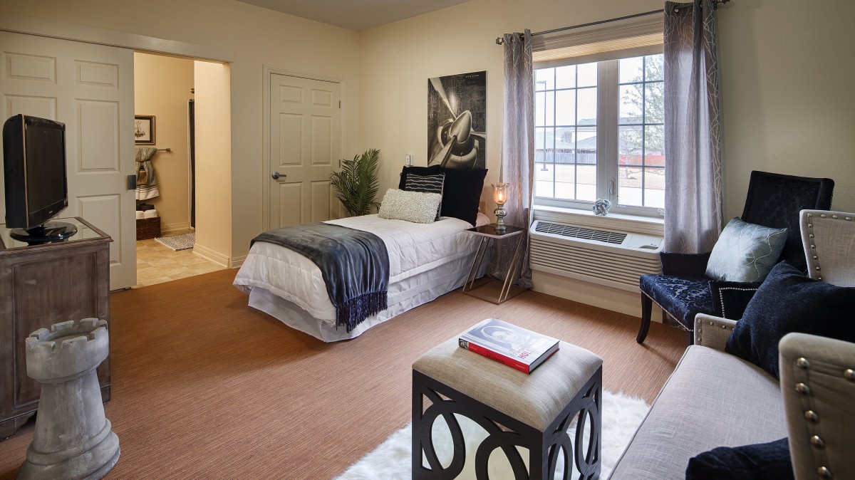 A cozy bedroom with a single bed, decorated with modern furnishings and a large window.