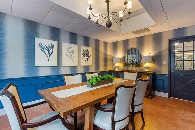 A modern dining room with a wooden table, elegant chairs, and decorative artwork on the walls.