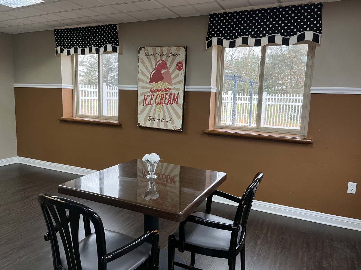 A cozy dining area with a table and chairs, featuring artwork and polka dot curtains.