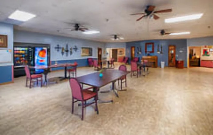 A spacious dining area with tables and chairs, decorated with wall art and equipped with ceiling fans.
