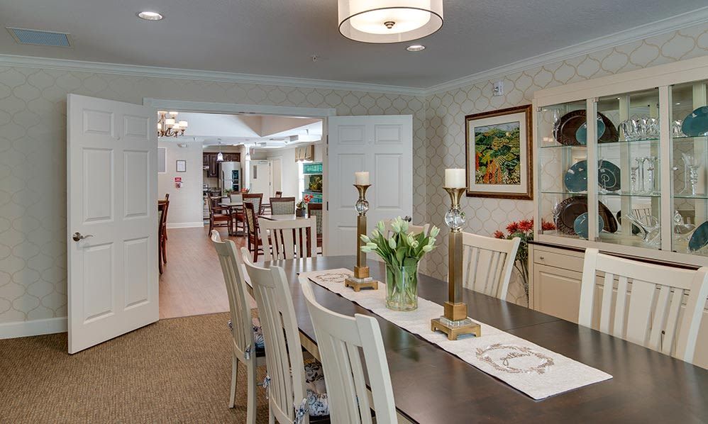 A well-decorated dining room with a long table, chairs, and elegant lighting.