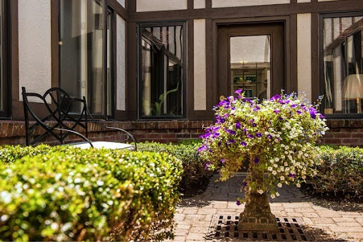 A vibrant courtyard featuring a flower arrangement, surrounded by well-maintained greenery and elegant architecture.