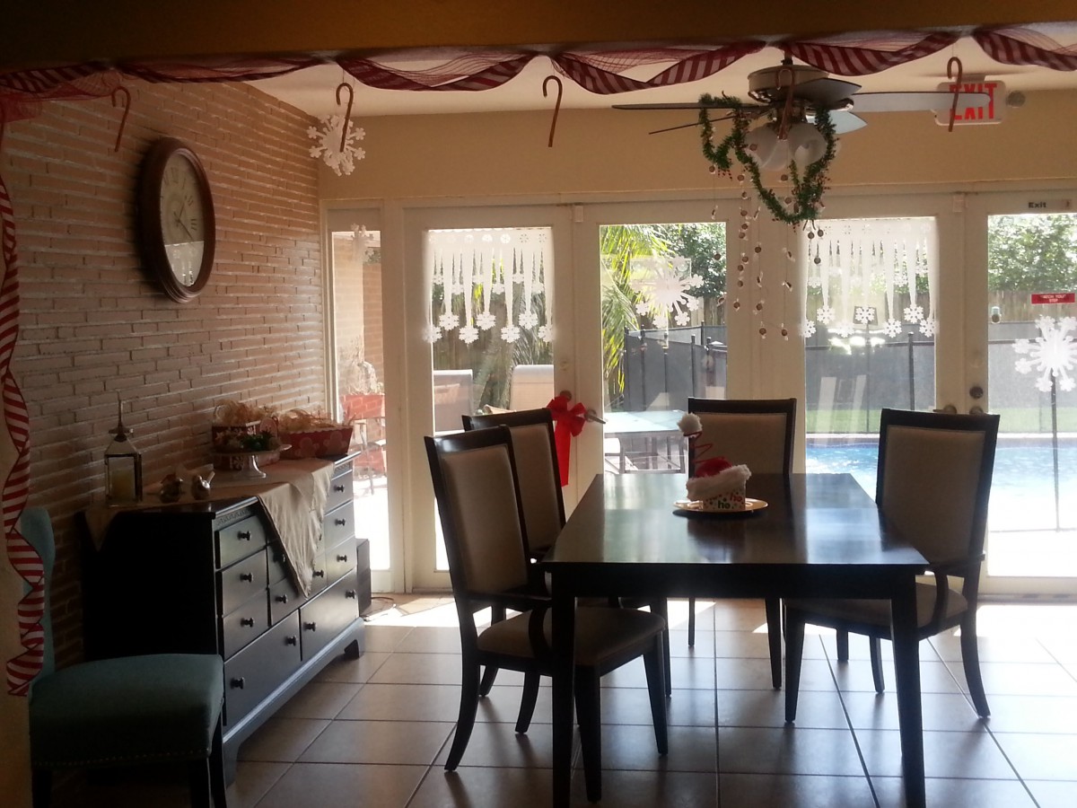 A cozy dining room decorated with hanging ornaments and a view of the backyard through large windows.