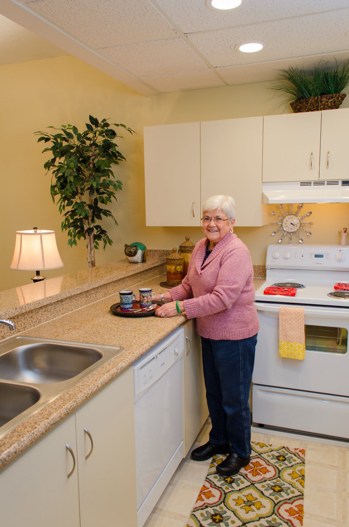 An elderly woman is standing in a cozy kitchen, preparing to cook.