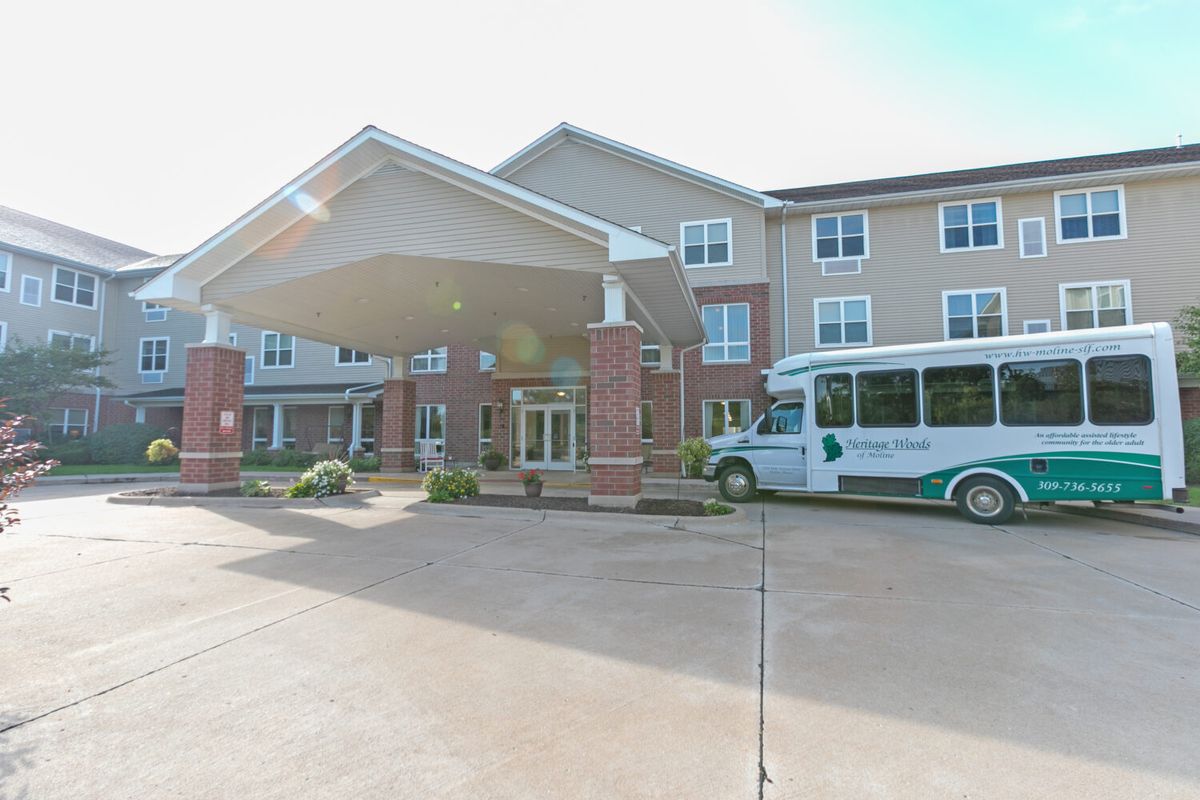 A retirement home's entrance with a shuttle bus parked outside.