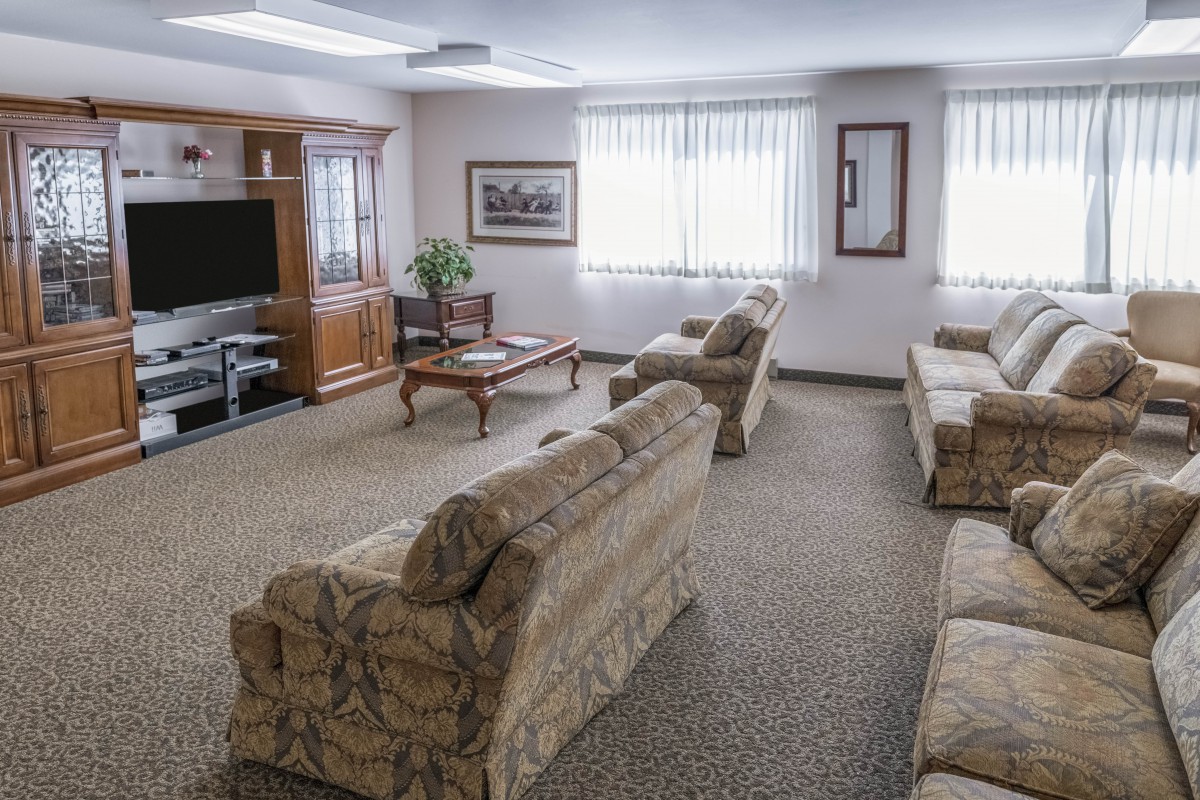 A cozy living room featuring multiple sofas, a coffee table, and a large TV.