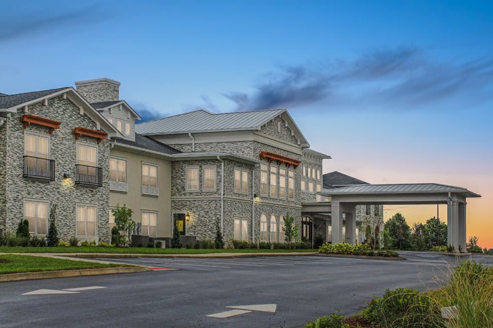 A modern residential building with a stone facade and well-maintained landscaping.
