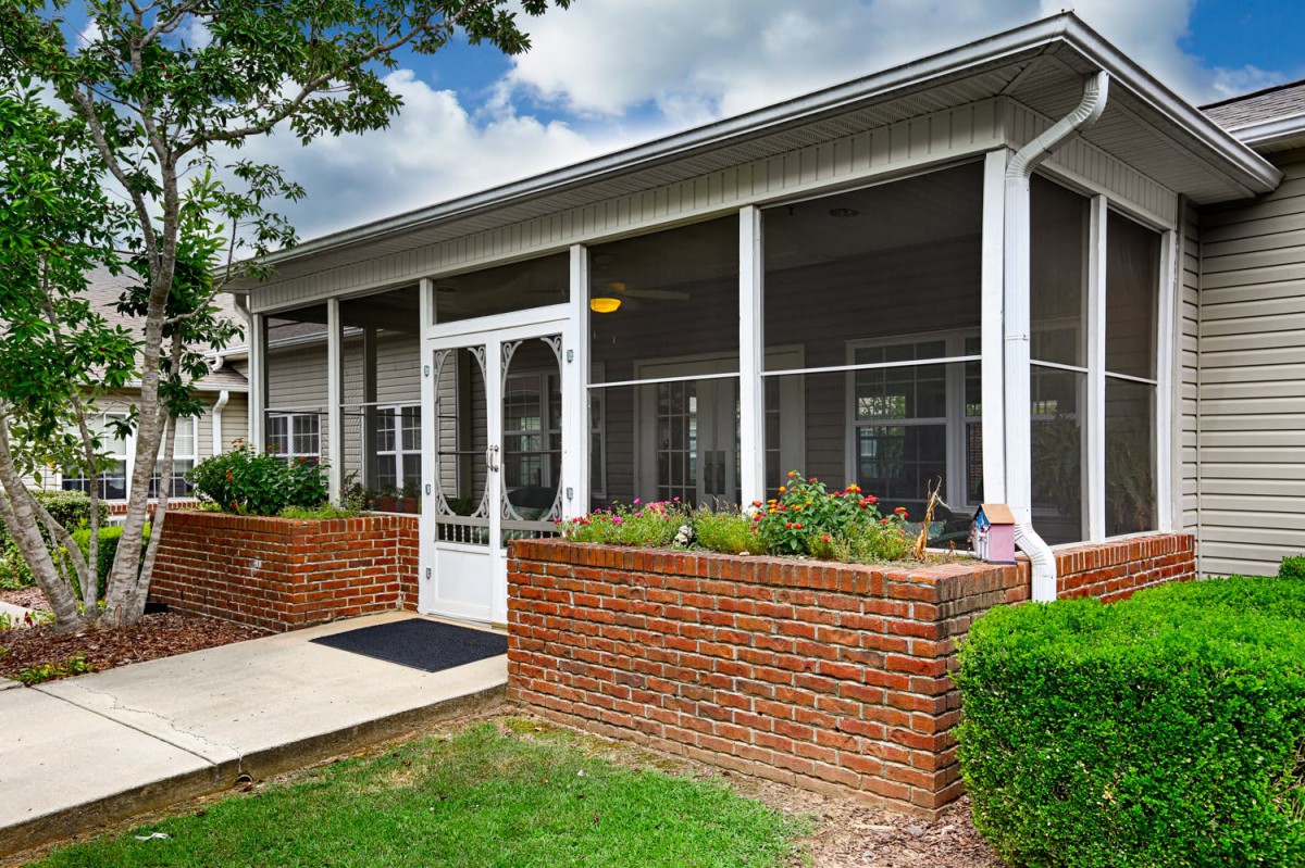 Screened porch with brick wall and entrance.