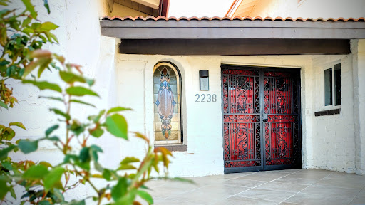 A welcoming entryway featuring decorative iron doors and a neatly landscaped front.