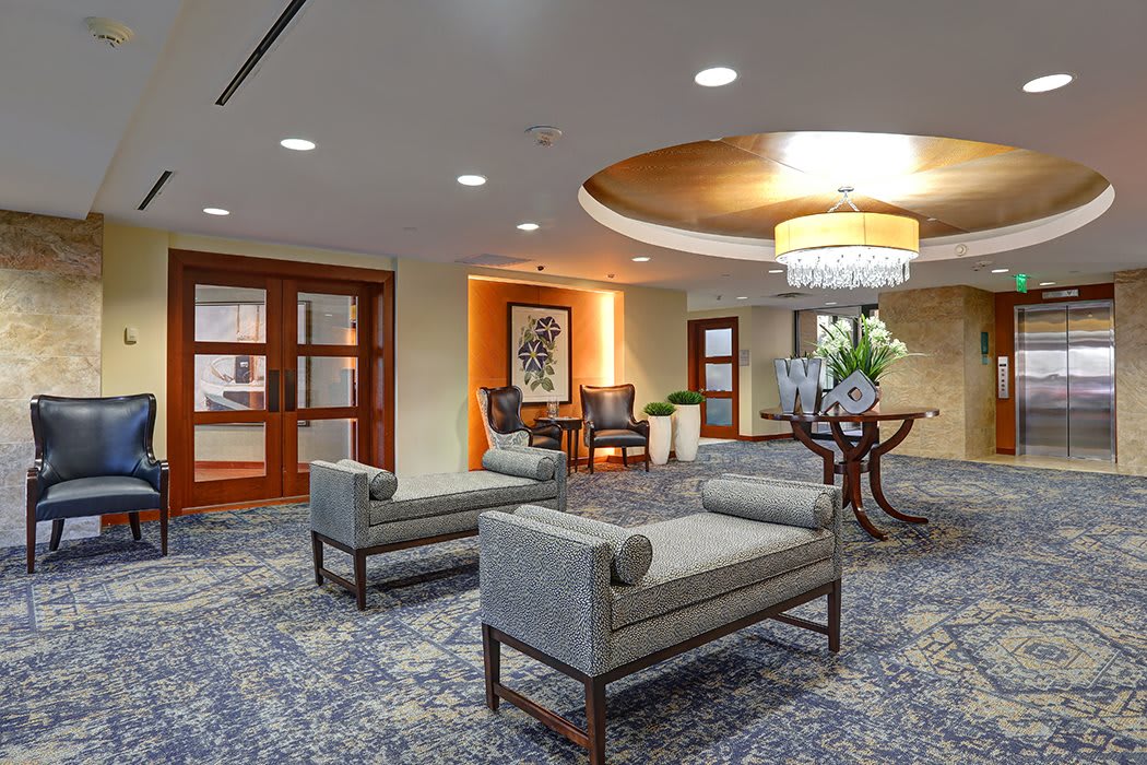 A stylish hotel lobby featuring modern seating and a chandelier.