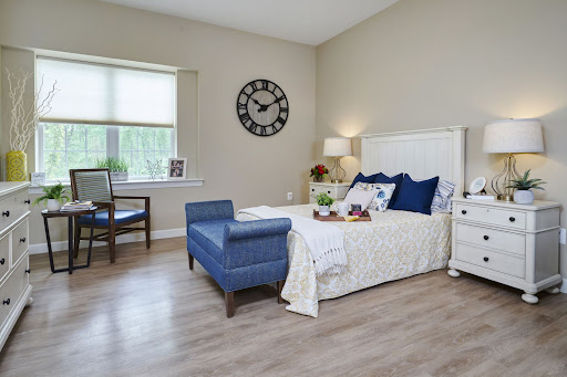 A serene and stylish bedroom featuring a blue and white color scheme, complemented by natural light and modern furnishings.