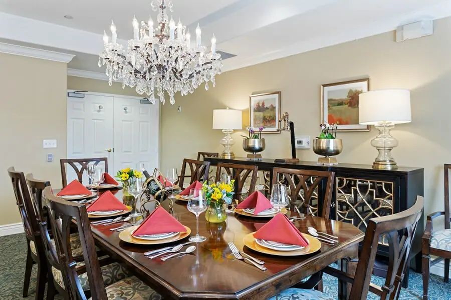 A beautifully set dining room with a chandelier and elegant table settings.