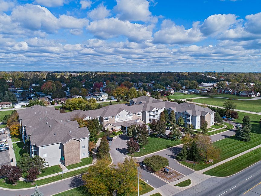 Aerial view of a suburban neighborhood with residential buildings and green spaces under a partly cloudy sky.