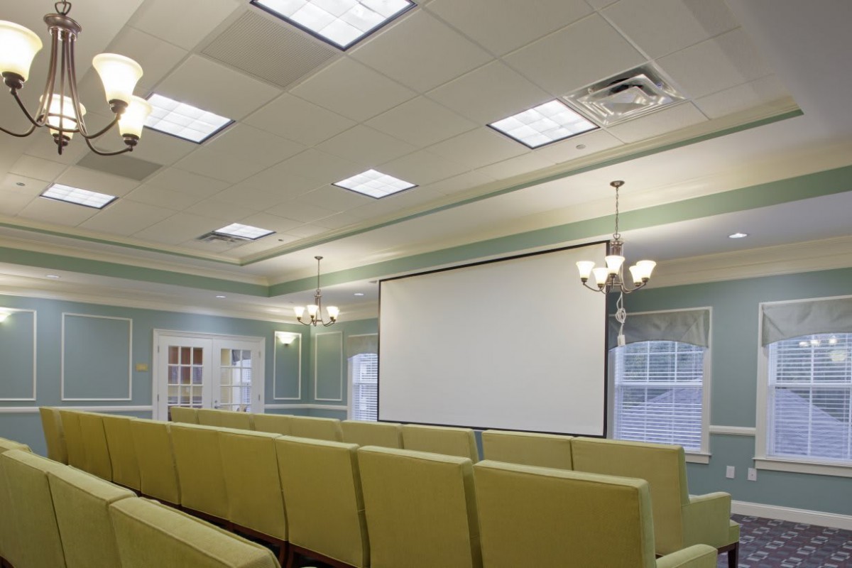 A well-lit conference room with arranged seating and a large projector screen.