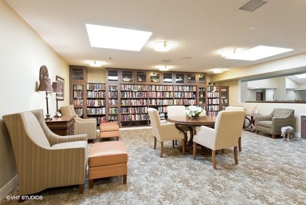 A cozy library with bookshelves, comfortable seating, and a table for reading or study.