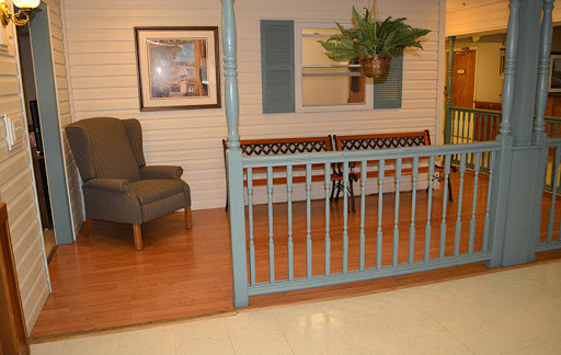 A cozy seating area featuring a blue fence, a bench, an armchair, and decorative plants.