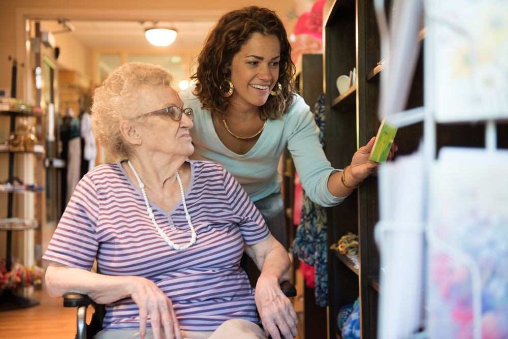 A caregiver assisting an elderly woman in a wheelchair at home.
