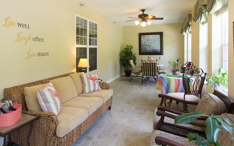 A cozy living and dining area with a sofa, ceiling fan, and colorful decor.