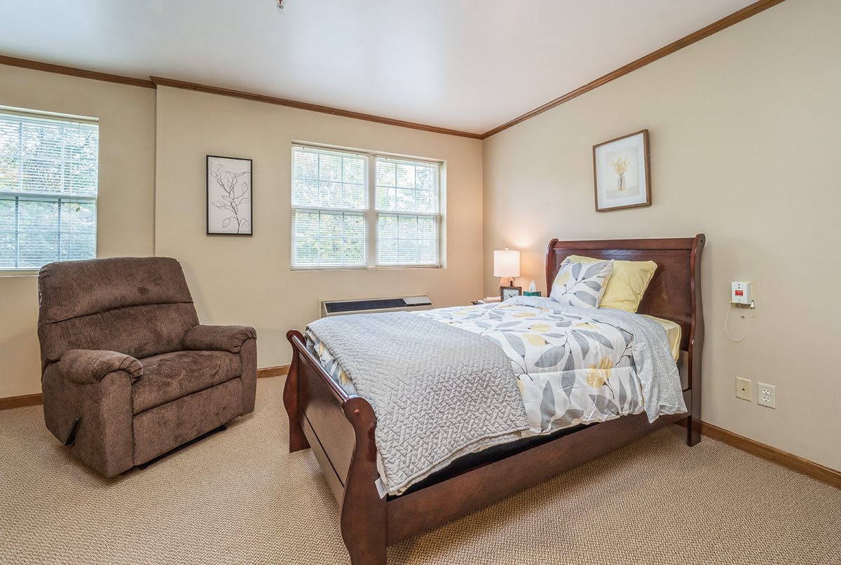 A cozy bedroom with a single bed, armchair, and framed artwork on the walls.
