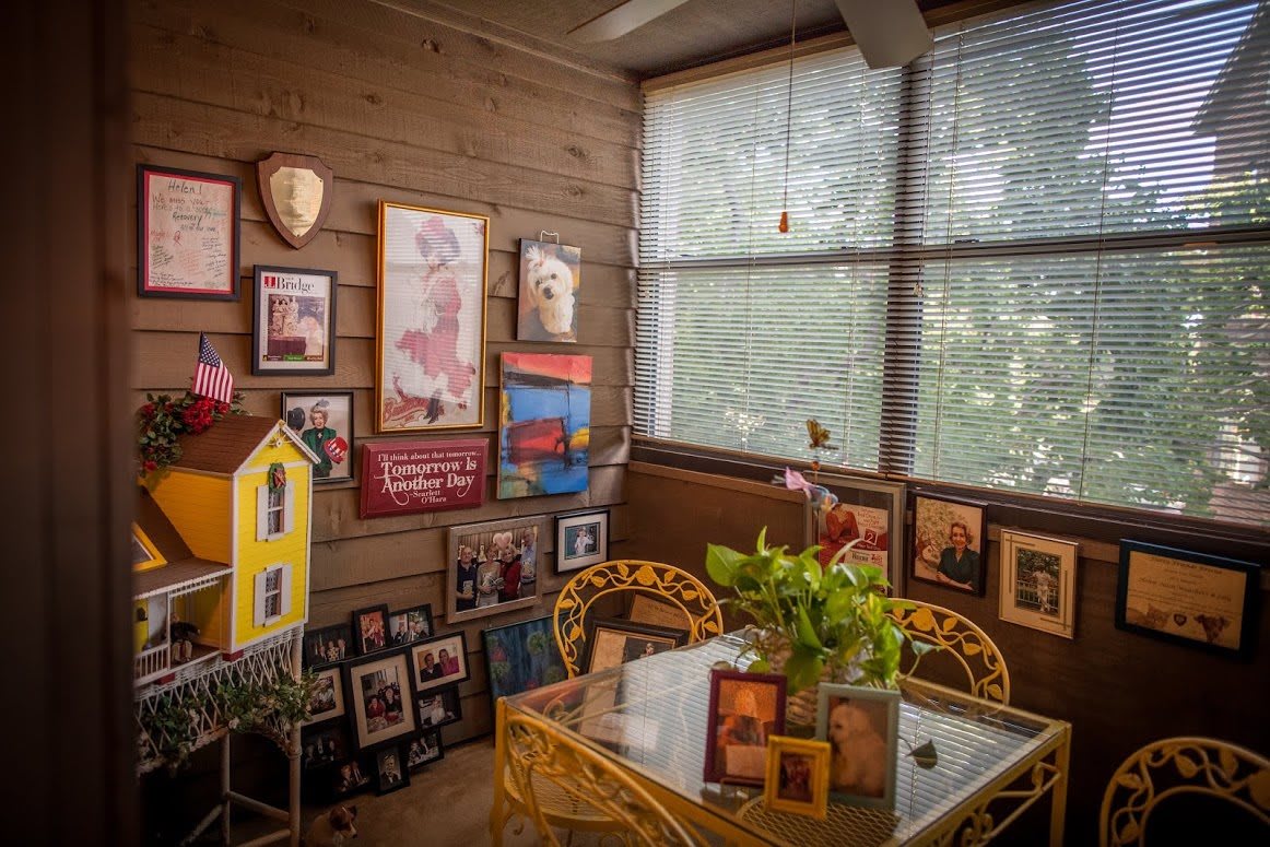 A cozy sunroom adorned with family photographs and artwork, complete with a table set for relaxation and indoor plants.