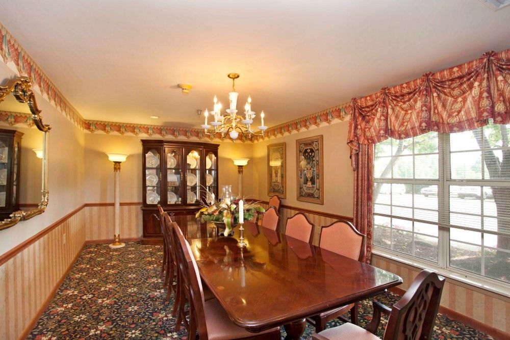 Elegant dining room with a long wooden table and chandelier lighting.