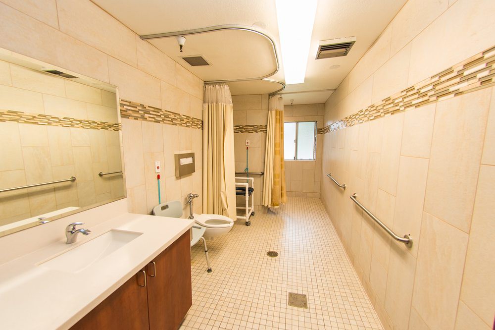 A spacious and accessible bathroom with a shower, sink, and grab bars.