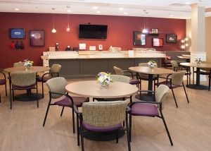 A cozy dining area with round tables, chairs, and a decorative arrangement on each table.