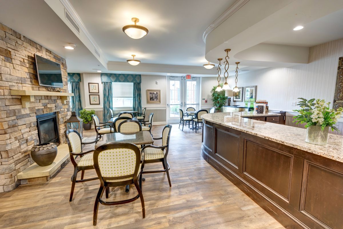 A cozy dining area featuring several tables and chairs, a bar counter, and stylish lighting fixtures.