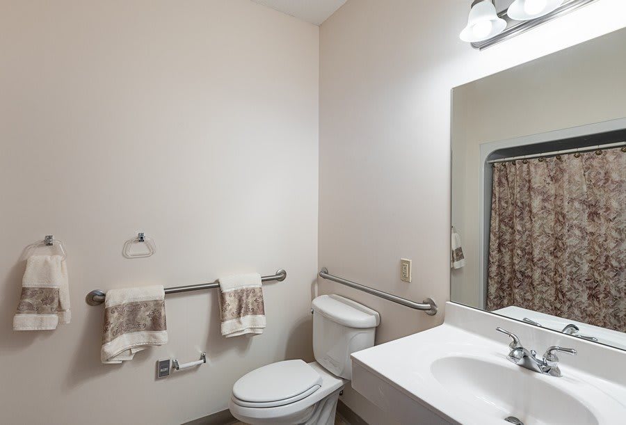 A clean and simple bathroom with a toilet, sink, and mirror.