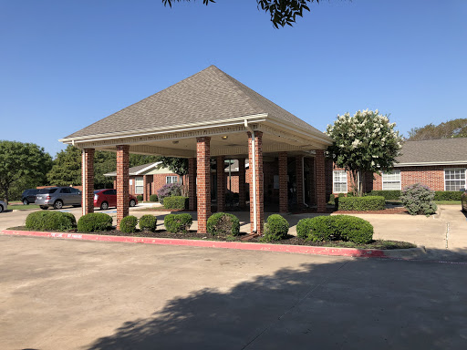 A welcoming entrance to a commercial building with a covered area and well-maintained landscaping.