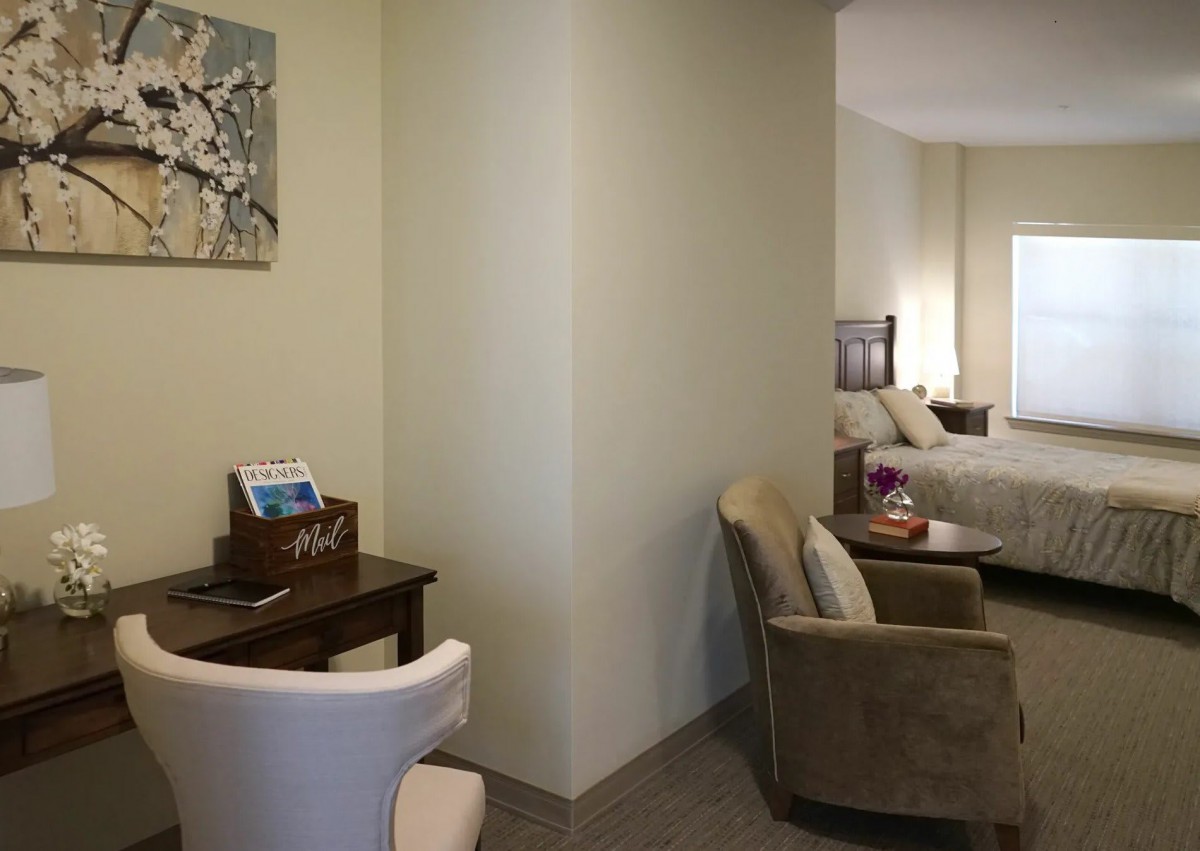 A cozy hotel room featuring a comfortable seating area, a work desk, and a neatly made bed.
