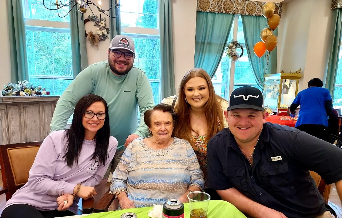 A family gathering indoors with everyone smiling and enjoying each other's company.