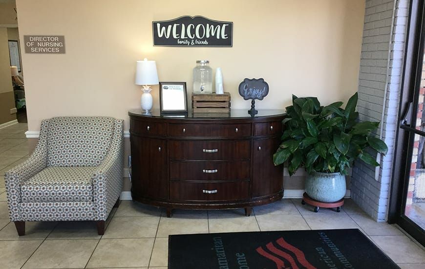 A welcoming lobby area with a wooden dresser, decor items, and a potted plant.
