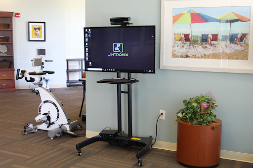 A mounted television on a mobile stand, set up in an exercise area.